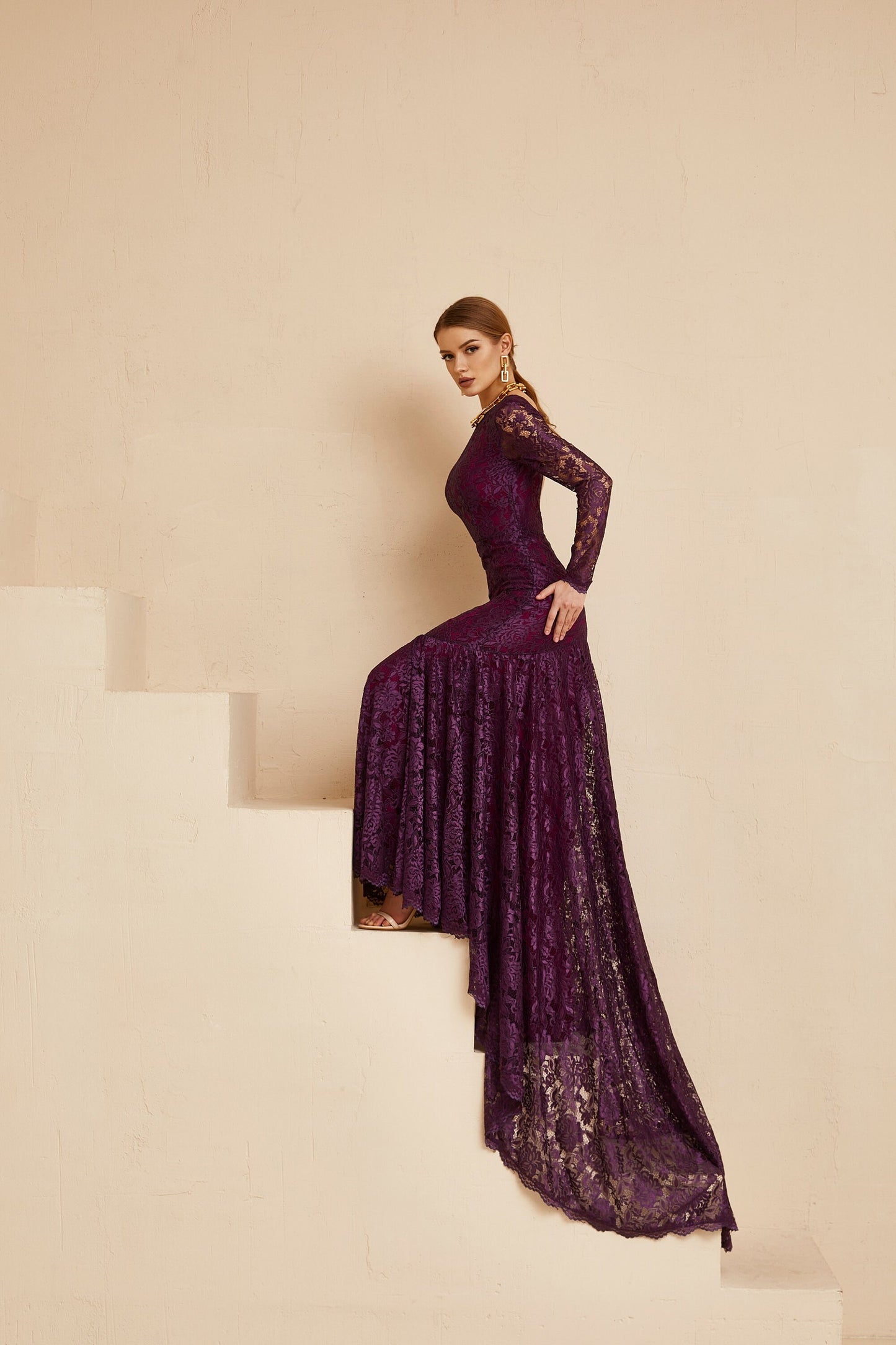 Purple evening dress with open back, long sleeves and dramatic train.