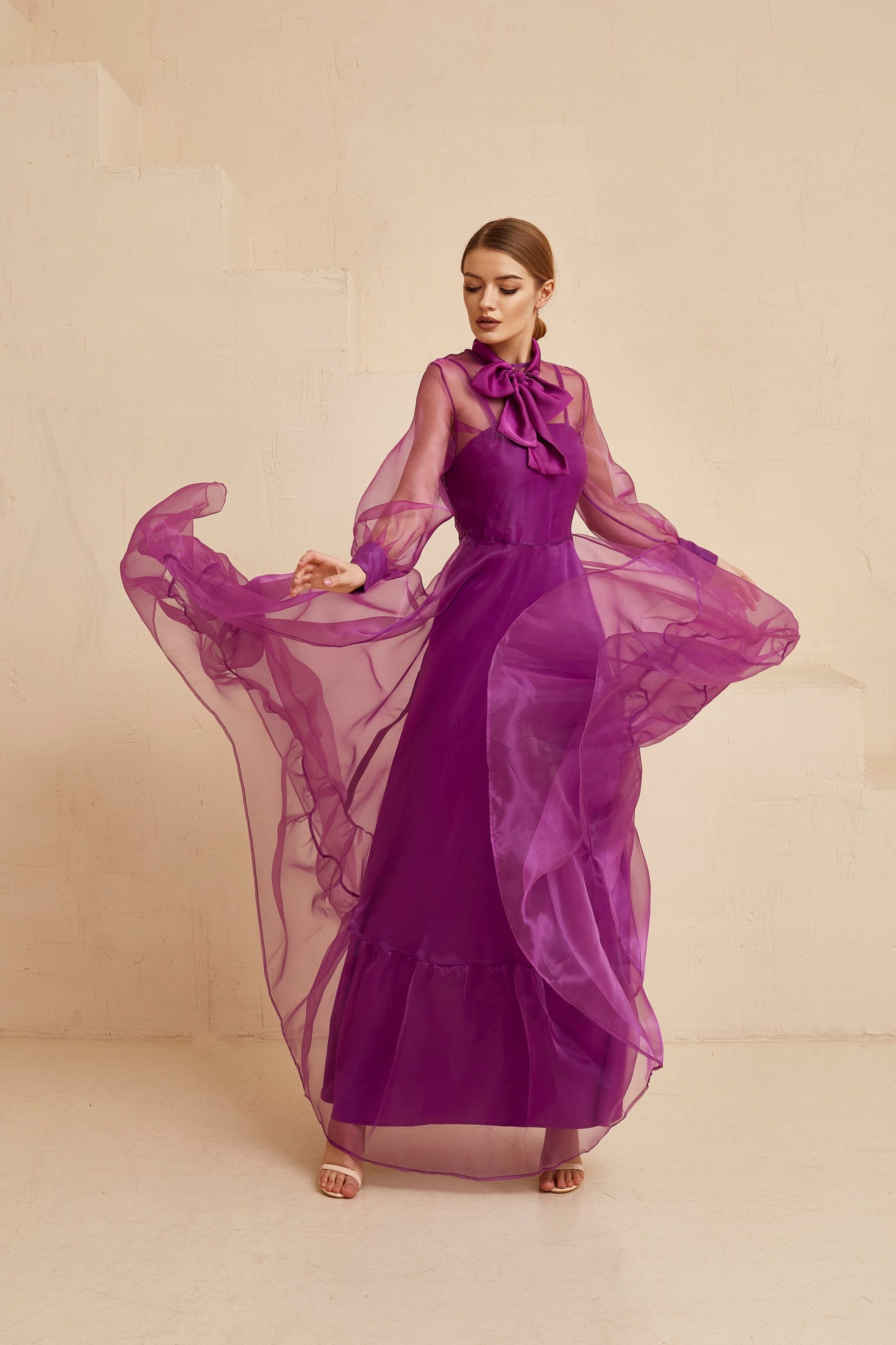 Purple bohemian dress made from organza fabric. This evening gown has natural waistline, maxi fit and flare skirt, and long sleeves. Also silk bow on neck.